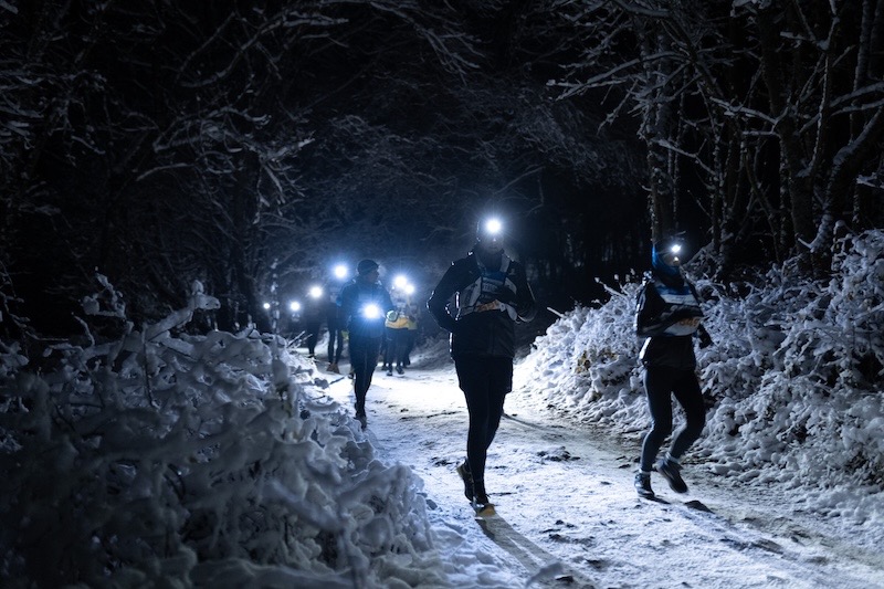 Trail runner wearing a bright running headlamp at night on road and trail.