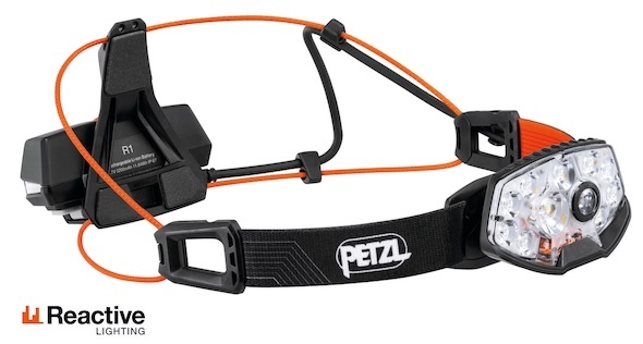 Trail runner wearing a bright running headlamp on a dark trail for night training.