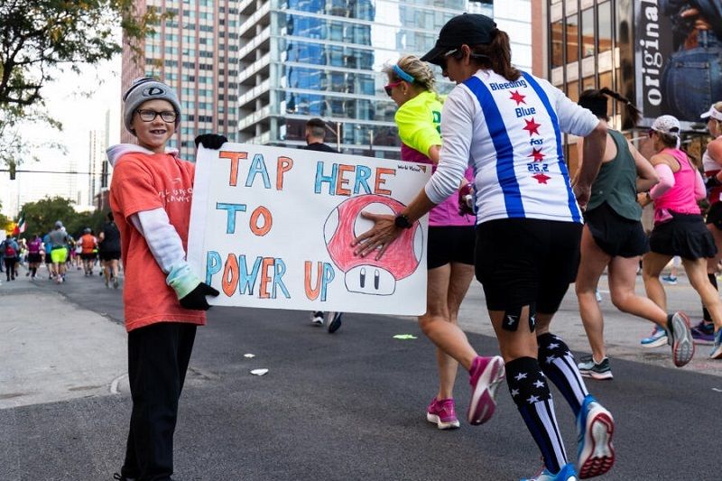 High-energy crowd cheering along the Chicago Marathon course near the course map signage.