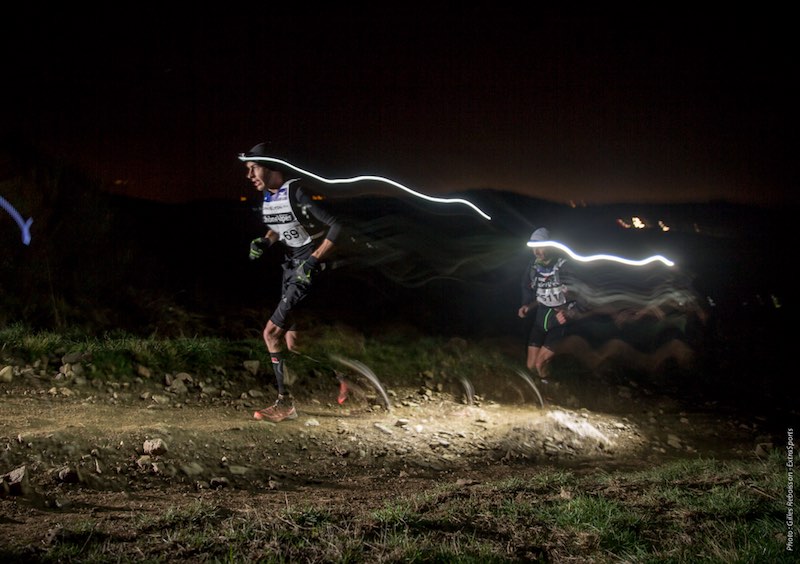 Trail runner racing the SaintéLyon 82 km night trail through winter darkness in France.