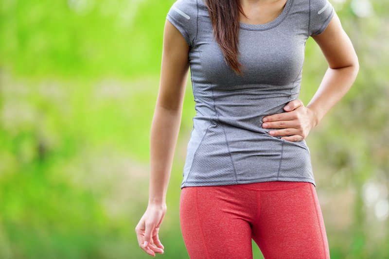 Runner holding side stitch during a run, showing fast relief and prevention techniques.