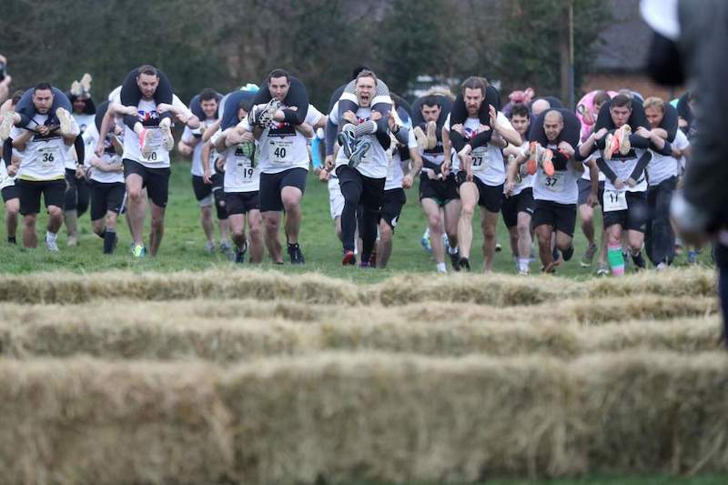 Runner carrying a partner during a wife carrying race, a wild endurance running challenge.