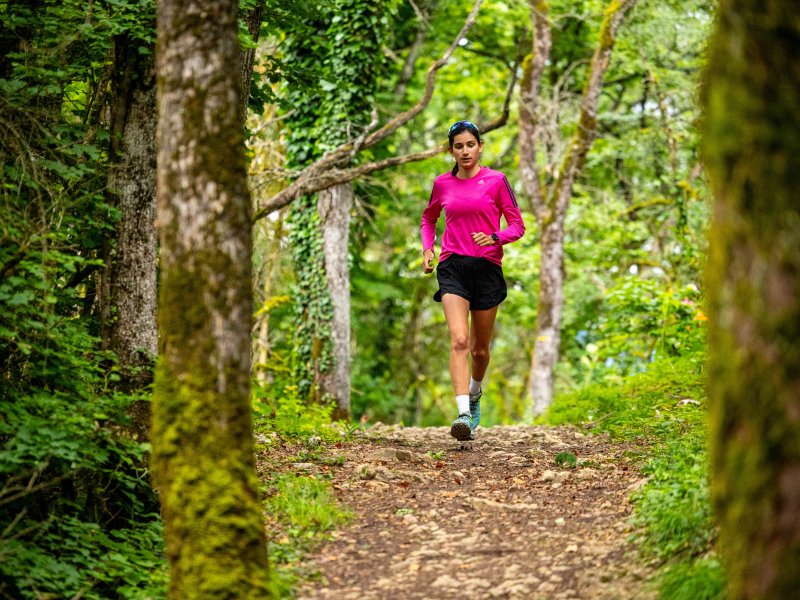 Woman running alone on a quiet path, following safety tips to run confidently outdoors.