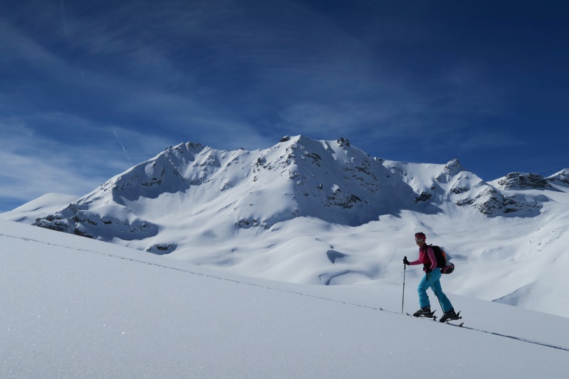 Trail runner ski touring uphill through snowy mountains for effective winter endurance training.