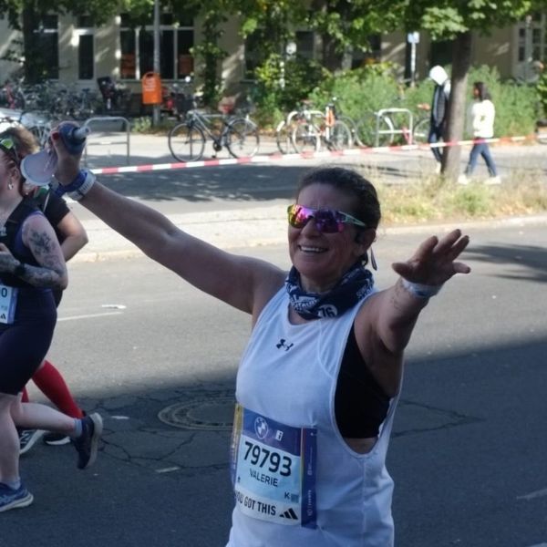 Valerie, 54, crossing the finish line of her first Berlin Marathon, celebrating a landmark running achievement.